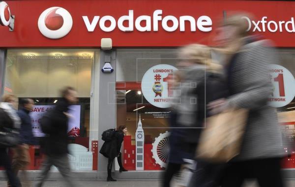 Varias personas caminan ante una tienda del grupo británico Vodafone. EFE