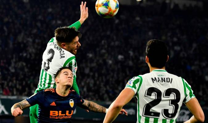 El defensa del Real Betis Javi García (i. detrás) salta por el balón con Santi Mina, del Valencia CF. EFE/Raúl Caro