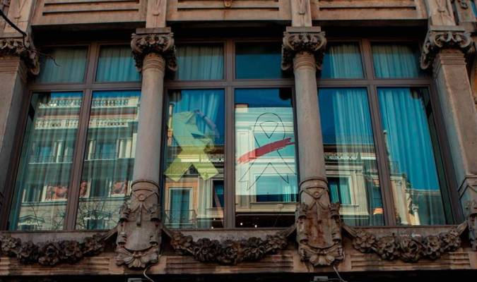 Un operario retira el lazo amarillo de una de las ventanas de la fachada del edificio de la Consellería de Economía. / EFE