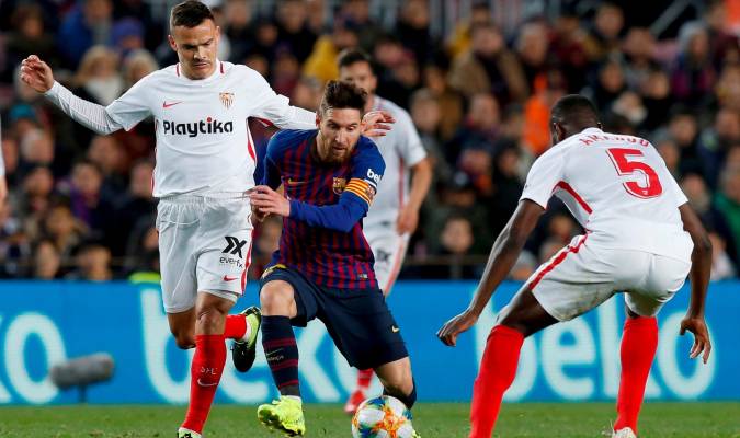 El delantero argentina del FC Barcelona, Leo Messi (c), intenta llevarse el balón ante los jugadores del Sevilla FC, Roque Mesa (i) y el francés Ibrahim Amadou. EFE/Enric Fontcuberta.