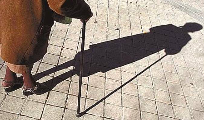 Una anciana proyecta una sombra que camina por la calle. / EFE