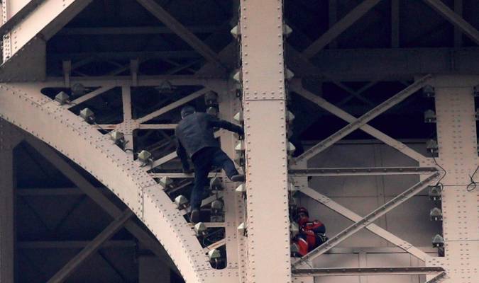  Un hombre escala la Torre Eiffel mientras varios bomberos tratan de detenerlo, este lunes en París. EFE/ Yoan Valat