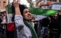 Una mujer muestra su cabello mientras unas personas sostienen una bandera de Irán anterior a la Revolución Islámica durante una protesta frente al Consulado iraní en Estambul ten protesta por la muerte de Mahsa Amini. EFE/EPA/ERDEM SAHIN