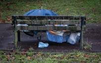 Un hombre duerme en un banco bajo la lluvia en una imagen de archivo. EFE/Javier Etxezarreta