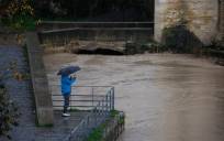 Una persona fotografía el río Guadalquivir junto al Puente Romano en Córdoba, con un caudal muy crecido tras las intensas y continuas lluvias de los últimos días. EFE/Salas