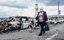 Una mujer camina delante de unos coches quemados en un puente de Irpin, a 7 de marzo de 2022, en Irpin (Ucrania). / E.P.