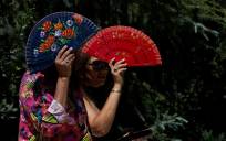 Dos mujeres se protegen del sol con abanicos . EFE/Chema Moya