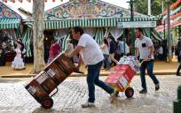 Unos trabajadores transportan por el Real diferentes bebidas para abastecer a las casetas. / Jesús Barrera