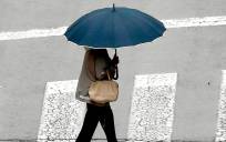 Una mujer con un paraguas por la calle. / EFE