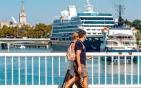 Dos turistas observan la entrada de dos cruceros al Puerto de Sevilla. / E.P.