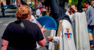 Una mujer abanica a un nazareno en los desfiles de Semana Santa de Sevilla / El Correo de Andalucia