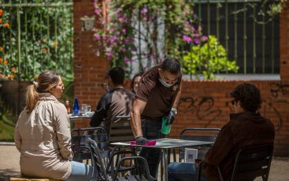 El propietario de un bar en Sevilla desinfecta la mesa de un velador a la llegada de unos clientes este lunes. / E.P.