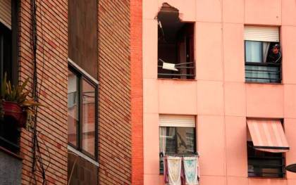Un joven observa la ventana por dónde entró el trozo de metal procedente de la explosión en la Petroquímica, causando la muerte de un vecino de este edificio. / EFE