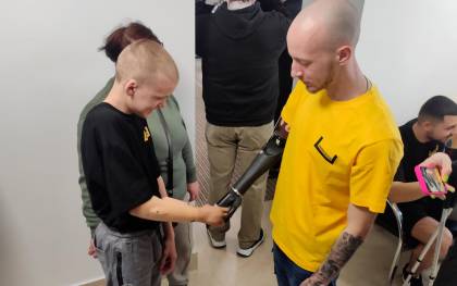 Dmytro, un adolescente de 13 años que perdió el brazo cuando ayudaba a su madre, saluda a Mykyta Baburkin, que tiene un brazo protésico biónico. EFE/Rotyslav Averchuk
