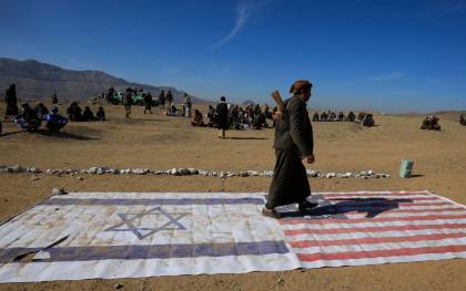 Un integrante de una tribu leal a los hutíes camina encima de las banderas de Israel y Estados Unidos durante un encuentro para combatientes recientemente reclutados el 22 de enero en las afueras de Saná. EFE/YAHYA ARHAB