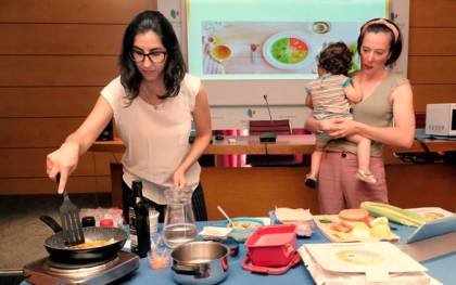 La nutricionista de Nestlé, Laura Álvarez, explica a una mamá con su bebé como realizar una receta.