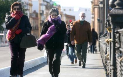 Dos ciudadanas se protegen del frío mientras caminan por el puente de Isabel II. / Antonio Acedo