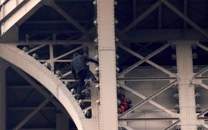  Un hombre escala la Torre Eiffel mientras varios bomberos tratan de detenerlo, este lunes en París. EFE/ Yoan Valat