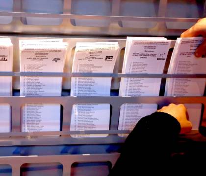 Un operario coloca papeletas electorales en una cabina. EFE/Alberto Estévez