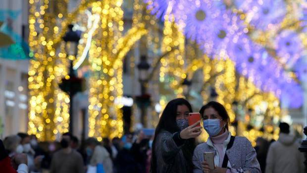 Dos mujeres se retratan en una abarrotada calle Larios de Málaga con motivo de las luces de Navidad / Efe - Álex Zea