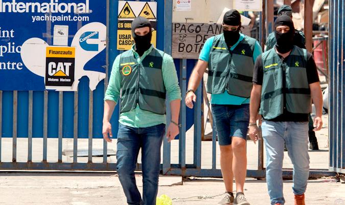 Agentes de la Guardia Civil tras el registro de unos almacenes en el Puerto de isla Cristina. / Raúl Caro-EFE