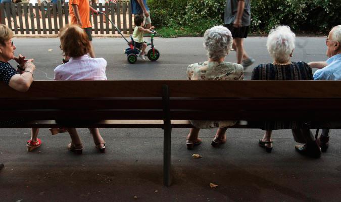 Un grupo de personas mayores, en un banco de una zona verde. / Julio Carbo (Efe)