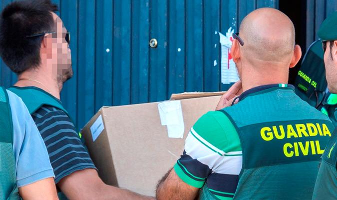 Agentes de la Guardia Civil portan cajas durante los registros realizados hoy en las dependencias de Magrudis, la nave industrial ubicada en el Polígono sevillano del Pino. EFE/Raúl Caro.