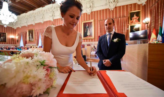 Una pareja firma el acta matrimonial tras contraer matrimonio en el Salón Colón del Ayuntamiento de Sevilla. / Jesús Barrera