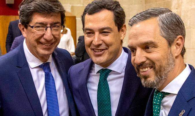 El presidente andaluz, Juanma Moreno (c), junto al vicepresidente, Juan Marín (i), felicitan al consejero de Hacienda, Juan Bravo (d), tras la aprobación del presupuesto. EFE/Julio Muñoz
