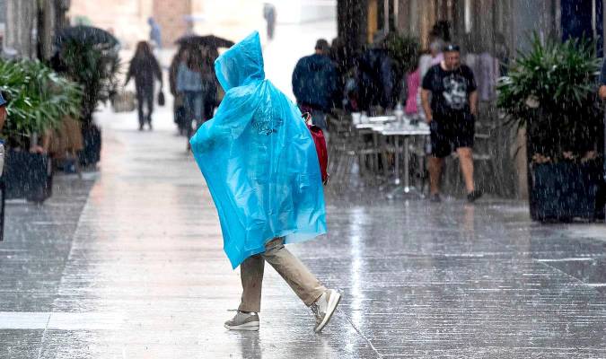 En la imagen de archivo, una mujer se protege de la lluvia con un chubasquero. EFE/Marcial Guillén