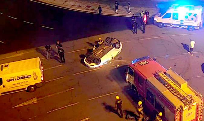 Imagen del coche volcado en la Glorieta Olímpica. / Emergencias Sevilla