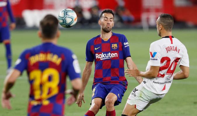 El centrocampista del Sevilla, Joan Jordán (d), disputa un balón ante el centrocampista del FC Barcelona, Sergio Busquets (c). EFE/ José Manuel Vidal