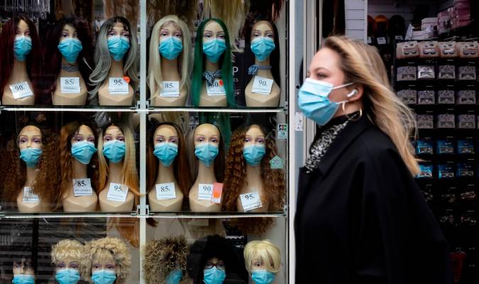 Una mujer ataviada con máscara sanitaria pasa frente a un escaparate en la que se muestran maniquís con mascarillas. EFE/ Ian Langsdon