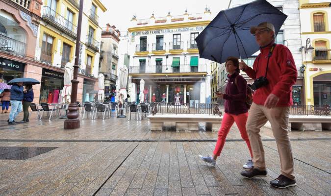Dos turistas con paraguas pasean por el centro de Sevilla. Foto: Jesús Barrera.