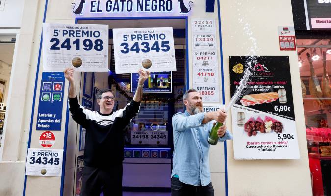 El propietario de la administración El Gato Negro de Málaga, Miguel Ángel Jiménez (i) junto a su trabajador Miguel Ponce (d) celebran los dos quintos premios. / Álex Zea