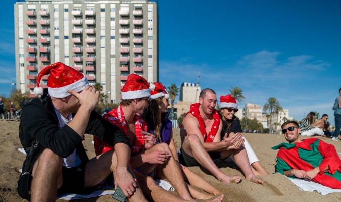 Unos turistas con gorros de Navidad disfrutan de las altas temperaturas en la playa de la Barceloneta, a 25 de diciembre de 2022. Lorena Sopêna / Europa Press