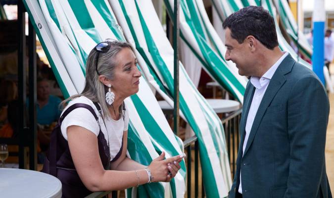 El candidato del Partido Popular a la presidencia de la Junta de Andalucía, Juanma Moreno, saluda a una mujer dentro de una caseta durante la Feria de Alcalá de Guadaira. / E.P.