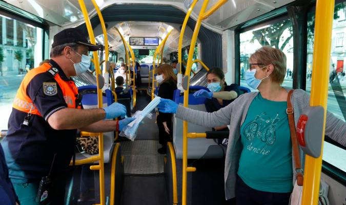 Miembros de protección civil de Málaga entregan mascarillas a los pasajeros de autobuses. / Álex Zea - E.P.