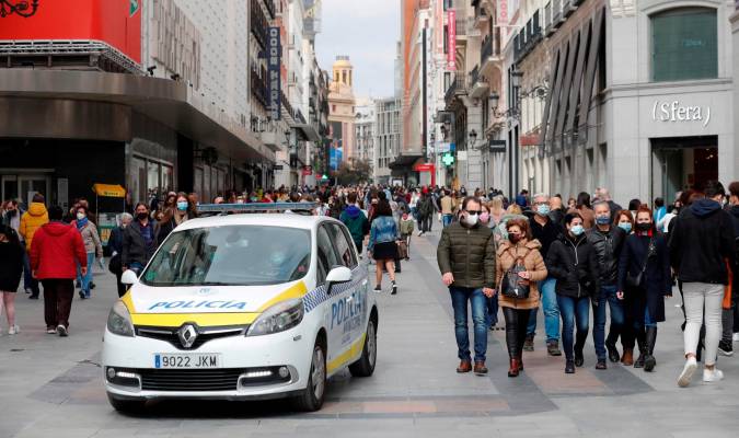 Un coche de la policía local circula entre los transeúntes que pasean por una de las calles comerciales anexas a la Puerta del Sol. EFE/Emilio Naranjo