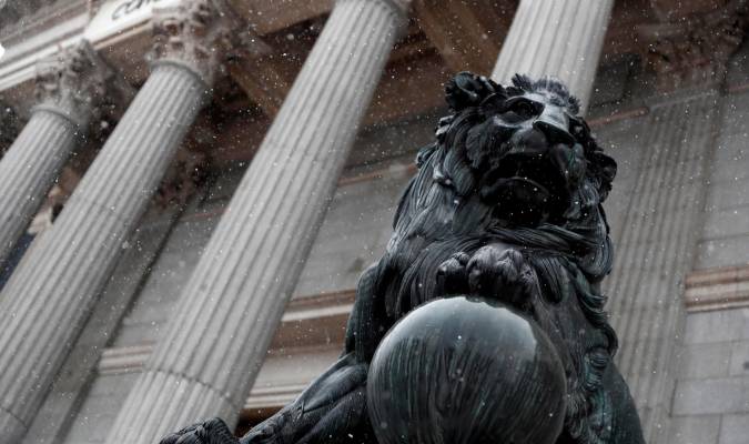 Uno de los leones del Congreso de los Diputados durante una fuerte nevada este viernes en Madrid. EFE/Mariscal