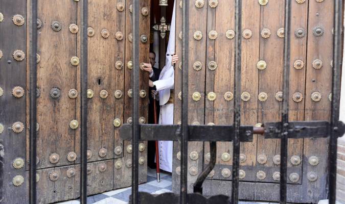 Un nazareno de la Sagrada Cena abre el portón de la iglesia para comenzar la estación de penitencia. Foto: Manuel Gómez. 