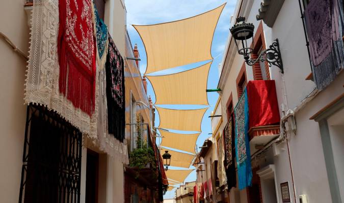 Vista de la calle Castelar de Cantillana con los balcones y ventanas adornados con mantones (Foto: Ateneo de Cantillana)