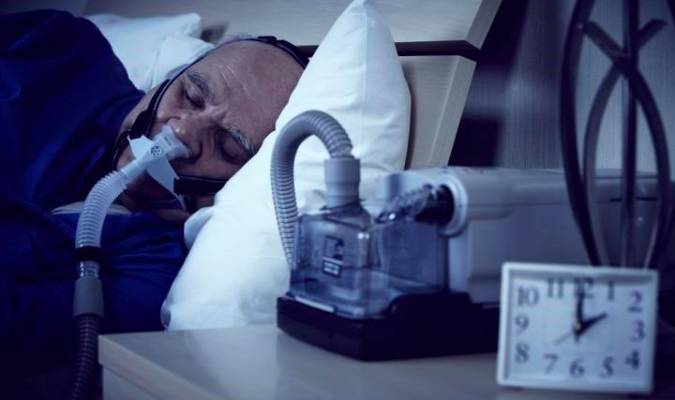 Un hombre duerme en su cama conectado a un dispositivo de presión positiva continua de las vías respiratorias. / E.P.