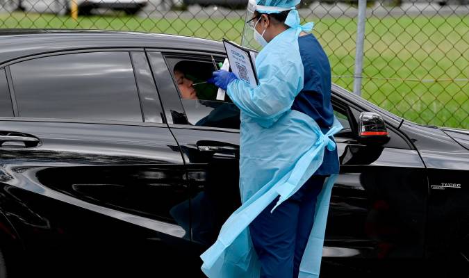 Un sanitario hace un test de antígenos en un coche.