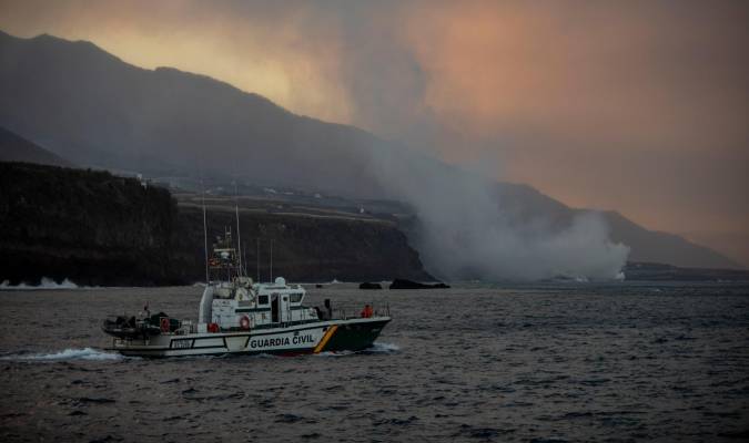 Un barco de la Guardia Civil navega cerca de la columna de humo y la lava del volcán de Cumbre Vieja a su llegada al Océano Atlántico. / E.P.
