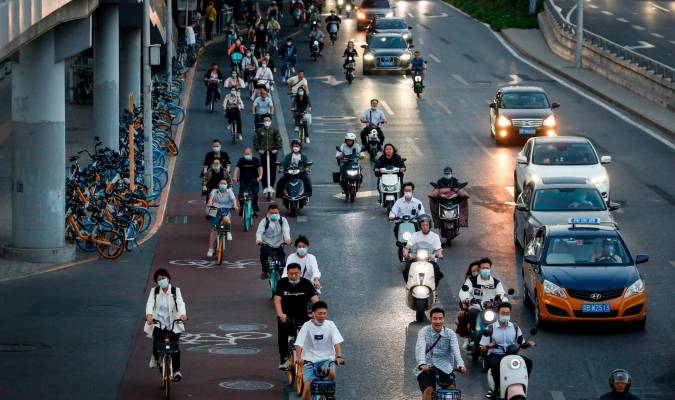 Personas circulan en bicicleta junto al tráfico en el distrito central de negocios de Pekín este 21 de septiembre. EFE