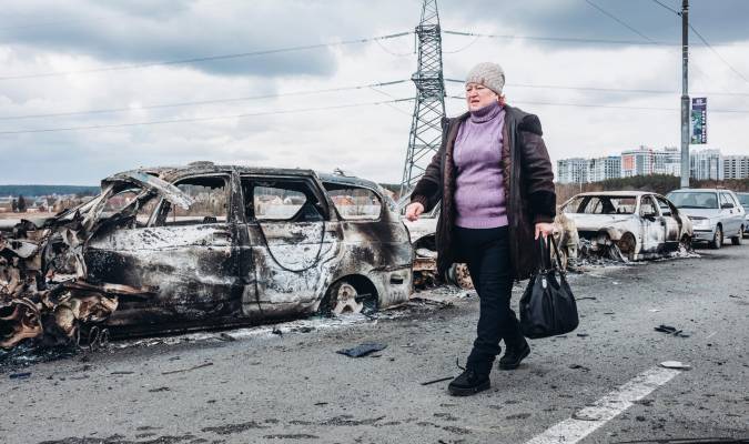 Una mujer camina delante de unos coches quemados en un puente de Irpin, a 7 de marzo de 2022, en Irpin (Ucrania). / E.P.