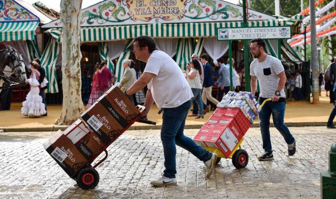 Unos trabajadores transportan por el Real diferentes bebidas para abastecer a las casetas. / Jesús Barrera