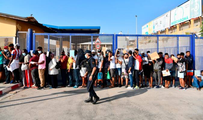 Un agente de Policía supervisa a cientos de personas, la mayoría marroquíes, que guardan cola en la oficina para tramitar los asilos situada en la frontera del Tarajal que separa Ceuta de Marruecos. Antonio Sempere