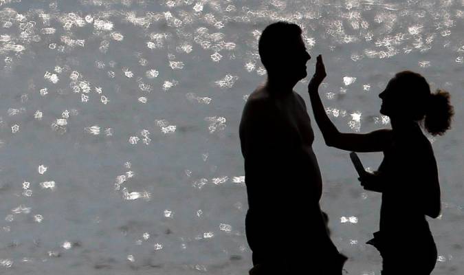 Una pareja se aplica crema solar a su llegada a la orilla de la playa de la Malvarrosa, en una foto de archivo. EFE/Kai Försterling